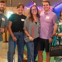 Five event attendees holding golf clubs and smiling at camera